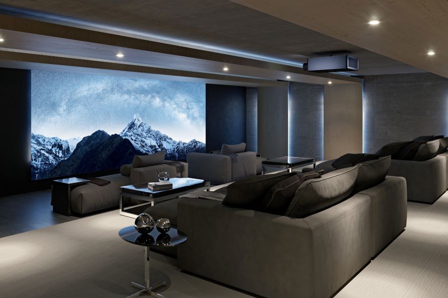 A large home theater with a Sony projector, large movie screen, and chaise lounges. 