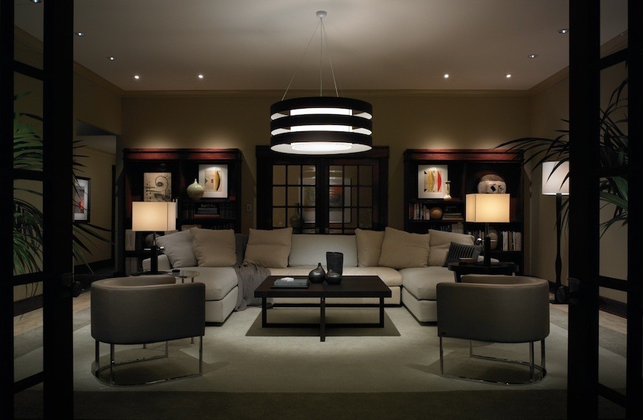  A dimly lit living room features architectural lighting fixtures such as a chandelier and lamps.