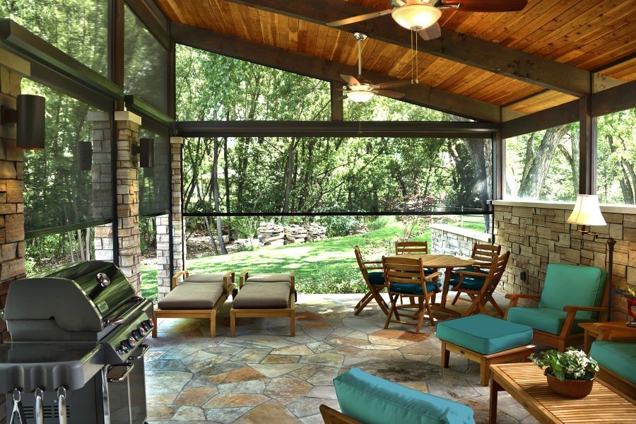 An outdoor patio area with wood ceilings, fans, and outdoor motorized shades.