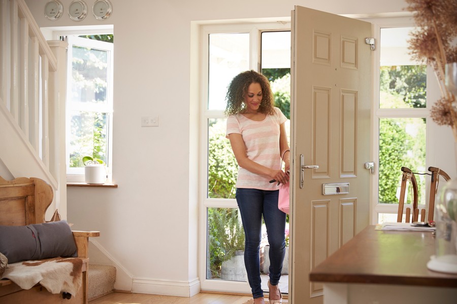 Woman entering her home through the front door and in the process of removing the key from the lock.