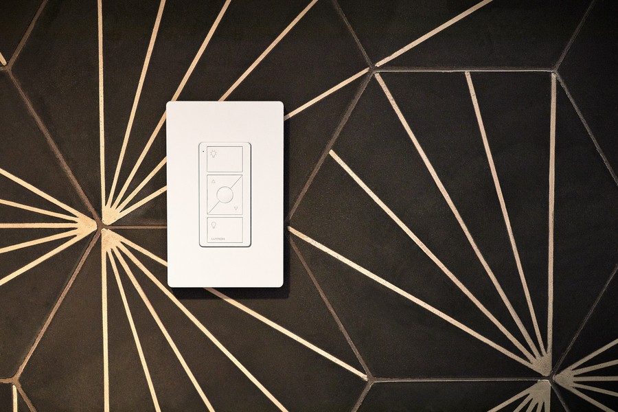 A Lutron lighting control switch on a black and gold tiles wall.