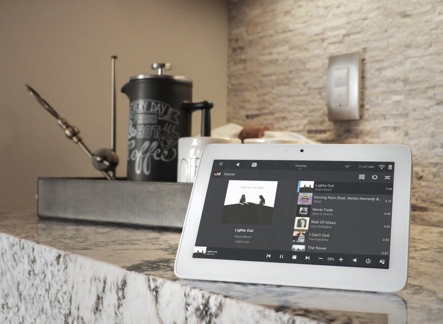 A touchscreen tablet on a kitchen counter displaying a Control4 interface.