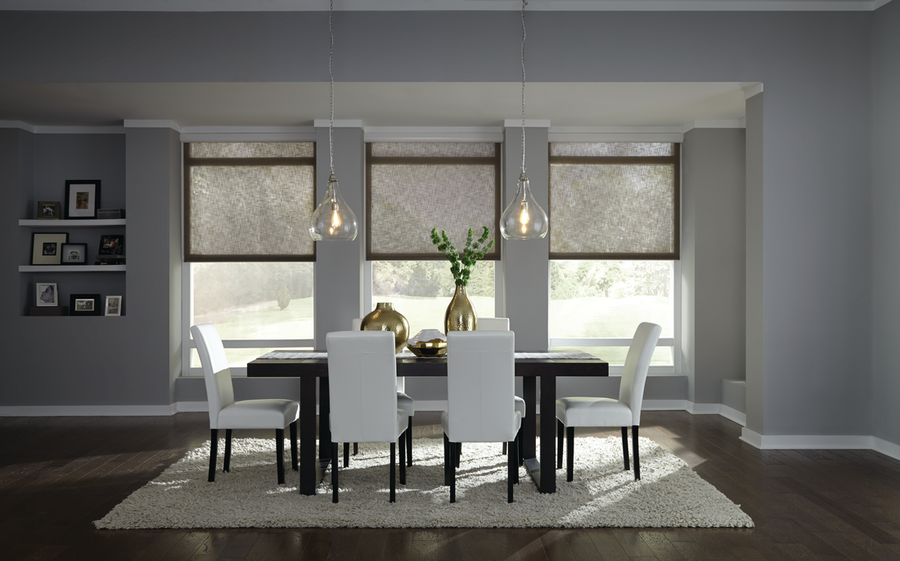 A dining room space featuring a dining table set with the motorized shades half-way lowered and dimmed lighting fixtures above the table.