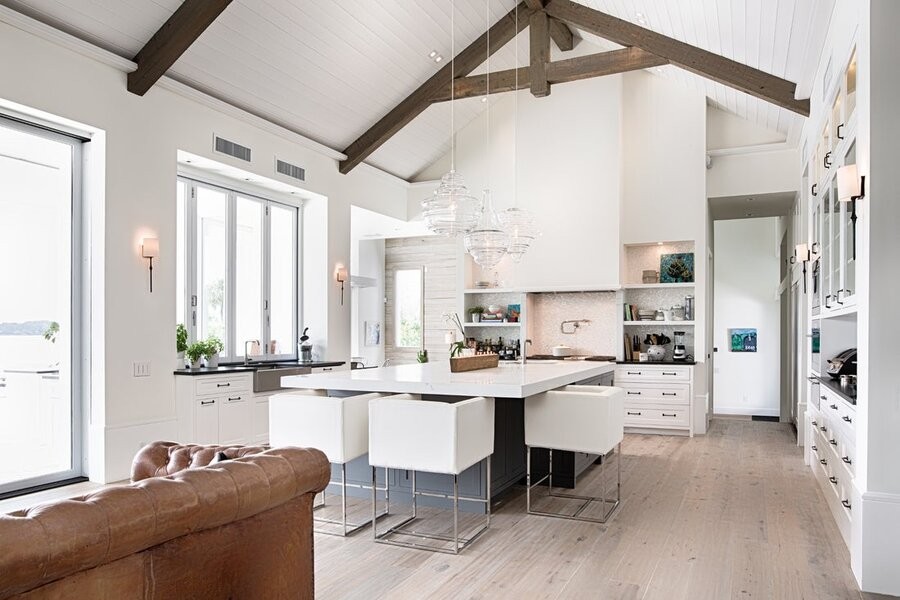 An open living room and kitchen space featuring a professional lighting design with Lutron lighting fixtures and solutions.