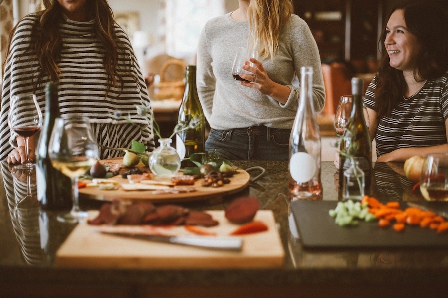 Friends congregated at a dining table with a plate of cheese, cured meats and fruit. 