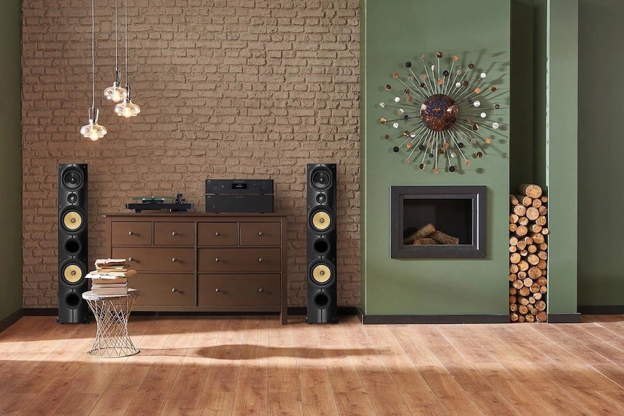 two loudspeakers and a turntable next to a dresser and a fireplace