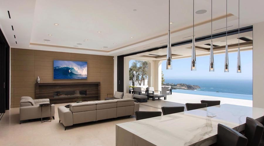 luxury media room featuring open-air access to patio overlooking the pool and ocean in the background.