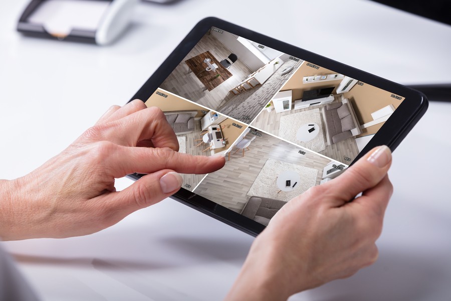 Person holding a tablet that display camera footage of four separate rooms in a house.