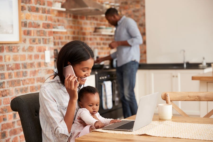 Woman with a baby in her lap talking over the phone